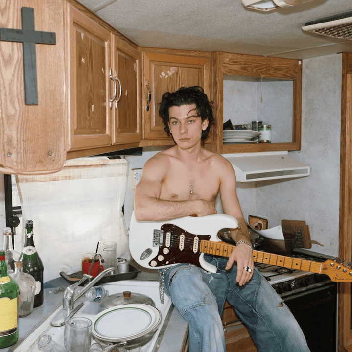 Henry Morris in a trailer kitchen with a white electric guitar